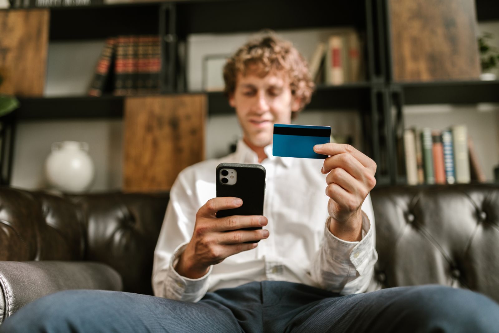 pexels-hero-phone Man smiling while shopping on his phone with a credit card